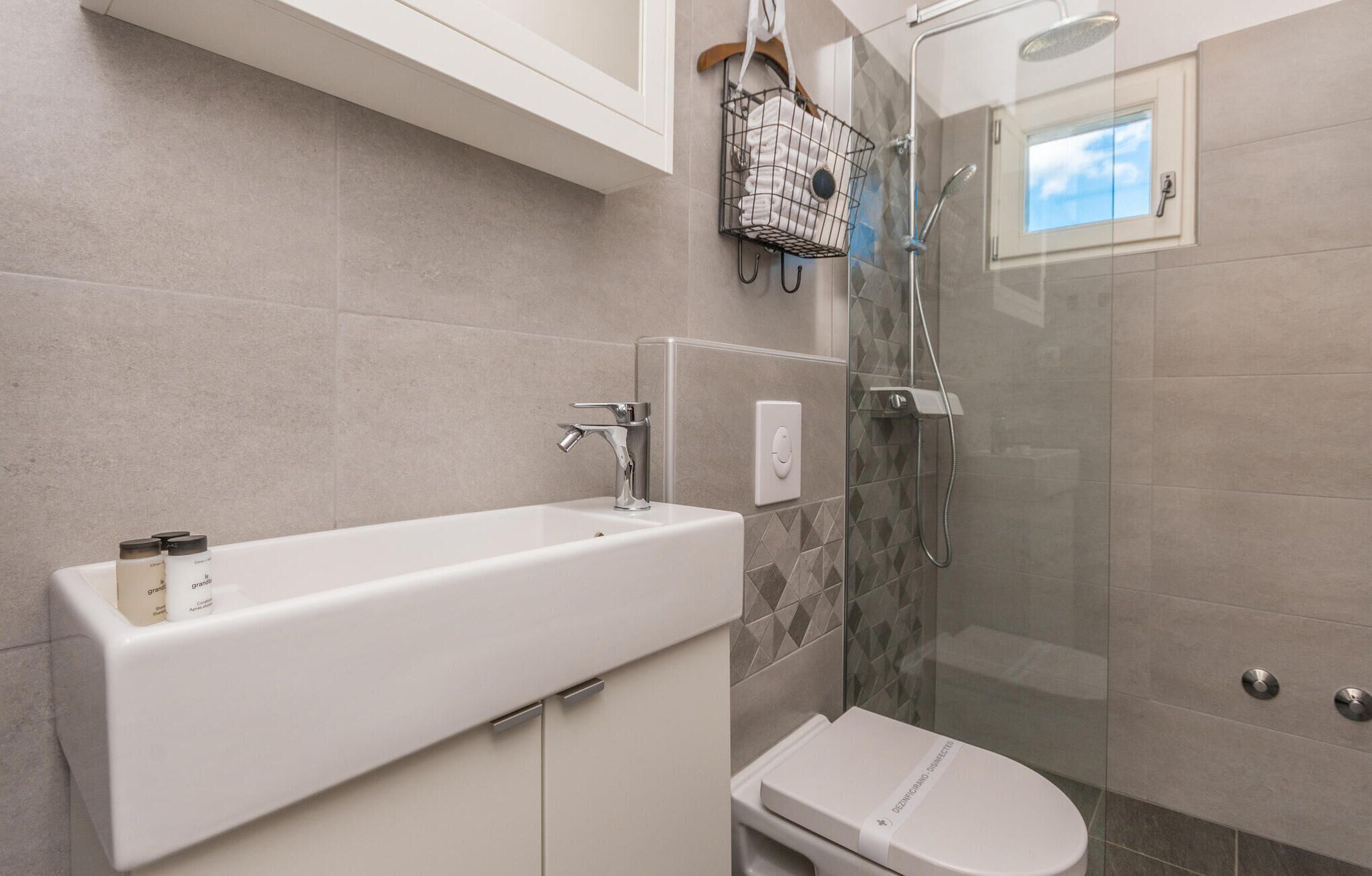 Une salle de bain avec un lavabo blanc, des toilettes et une douche à parois de verre.