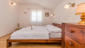 Un dormitorio con una cama de madera, un aparador de madera y una mesita de noche con una lámpara.