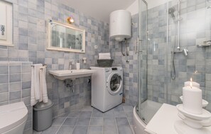 A modern bathroom with a glass shower enclosure, a built-in washing machine, and a toilet. - Amazing home in Polaca (Polaca)
