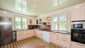 A kitchen with a herringbone floor pattern, stainless steel refrigerator, white dishwasher, and a black oven. - Lovely home in Briare with sauna (Briare)