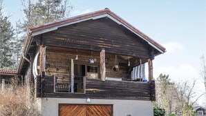 A rustic wooden cabin with a balcony, a garage, and a simple entrance. - Amazing home in Enviken with lake view (Enviken)
