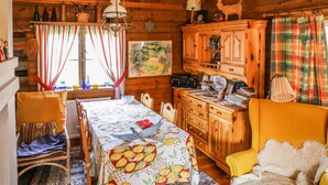 A cozy cabin interior with a dining area, wooden cabinets, and a window with curtains. - Amazing home in Enviken with lake view (Enviken)