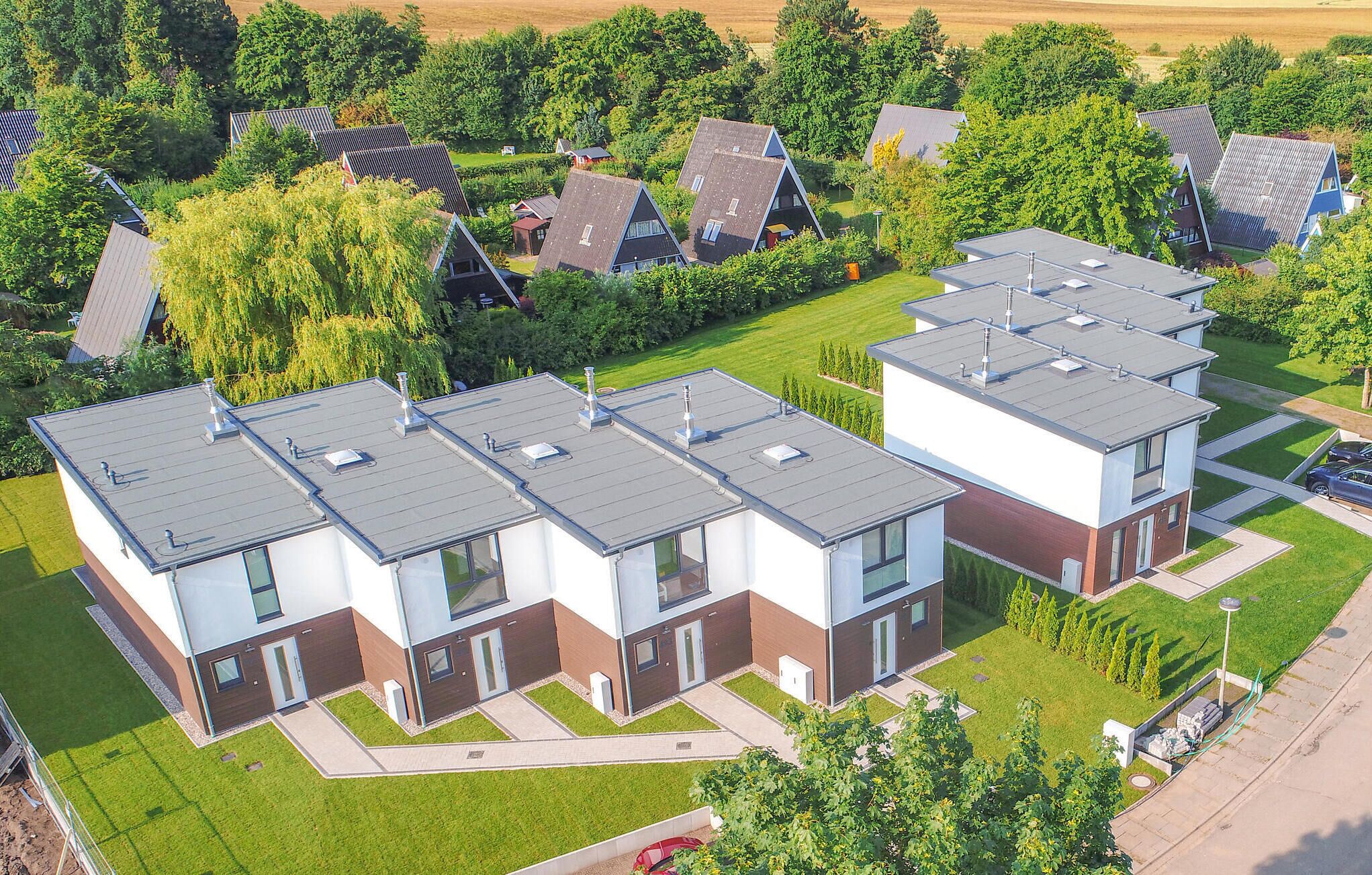 A modern residential complex with multiple two-story houses, each featuring a flat roof and a mix of white and brown exterior walls. - Amazing home in Damp with sauna (Damp)