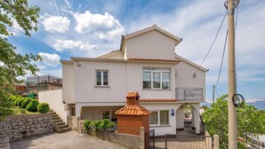 Ein zweistöckiges Haus mit Ziegeldach, Backsteinschornstein und Balkon.
