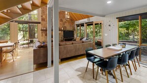 Een moderne woonkamer met een stenen openhaard, een grote bank en een eethoek met stoelen.