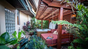 A cozy outdoor patio with a wooden swing, a hot tub, and lush tropical plants. - Love Nest - Luxury Studio in tropical gardens with koi ponds, waterfalls (Koloa)