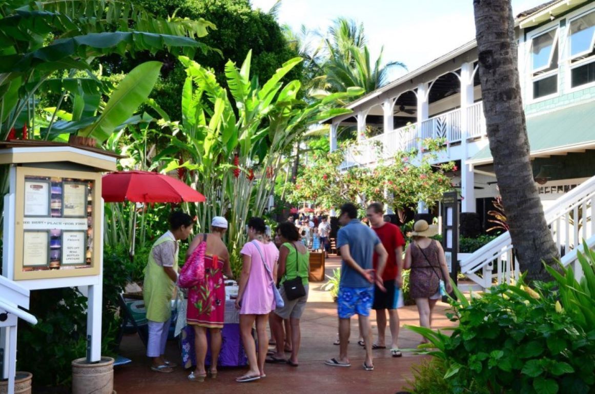 Un resort tropicale con una galleria coperta, vegetazione rigogliosa e un edificio con un balcone.