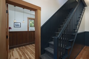 A wooden-floored hallway leading to a staircase with dark railings.