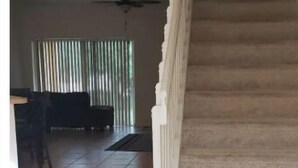 Un espacio habitable amplio con piso de baldosas, una escalera y un ventilador de techo.