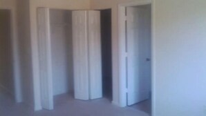 Una habitación con un armario grande, una puerta y una pared lisa.