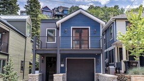 Ett modernt hus i två våningar med ett garage, stenpelare och en skylt med siffran ’55’.