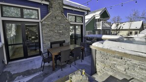 En eldstad i sten, en matplats utomhus och en bubbelpool i en snöig miljö.