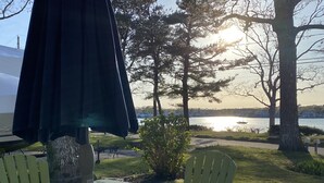 A table and chairs set outdoors with a view of trees and a body of water.