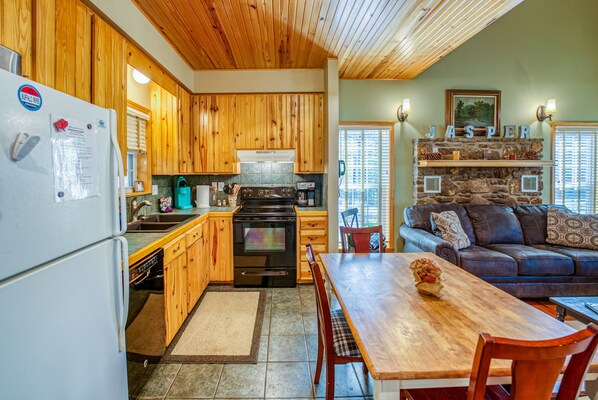 Una cocina con armarios de madera, una estufa y un comedor con mesa y sillas.