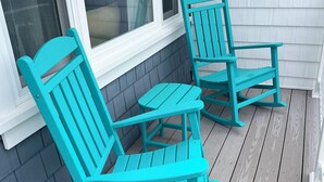 A porch with two turquoise rocking chairs and a small table.