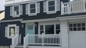 A two-story house with a front porch, white railings, and a garage.