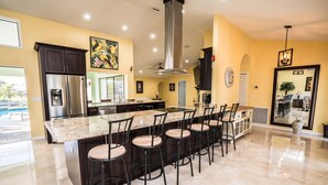 Una cocina moderna con una isla grande, armarios oscuros y vistas al exterior.