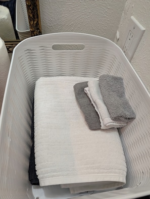 A white laundry basket with folded towels.