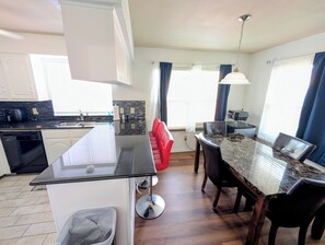 Une cuisine moderne dotée d’un îlot central, d’un coin repas avec une table en marbre et d’un four encastré.
