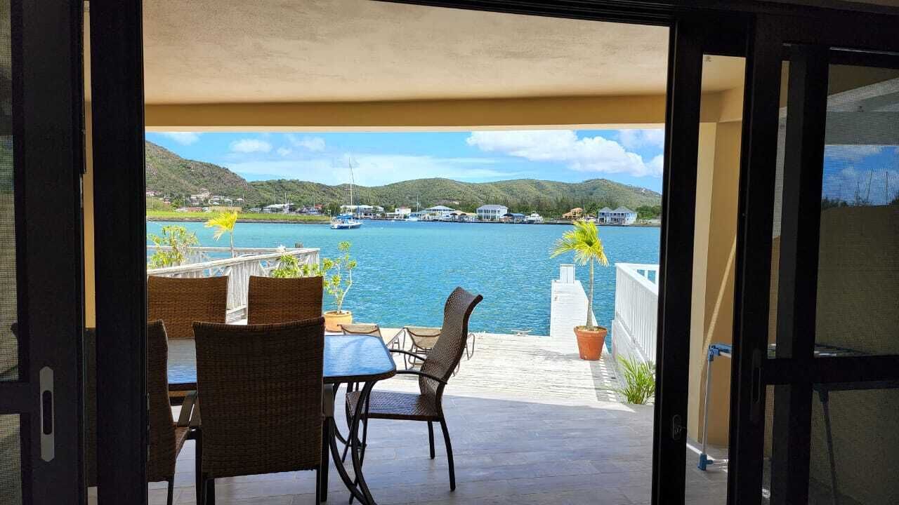 Un balcon donnant sur une étendue d’eau, avec des chaises et des plantes en pot.