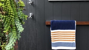 Ein Badezimmer mit Dusche, einem Handtuchhalter und einem gestreiften Handtuch sowie gerahmten Bildern an der Wand.