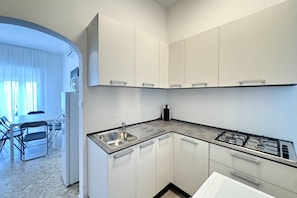 Una cocina moderna con armarios blancos, un lavamanos de acero inoxidable y una estufa a gas.