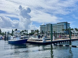 A marina with boats docked, a hotel with multiple balconies, and a clear sky.