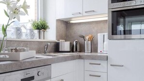 A modern kitchen with white cabinets, a built-in oven, and a stainless steel range hood.