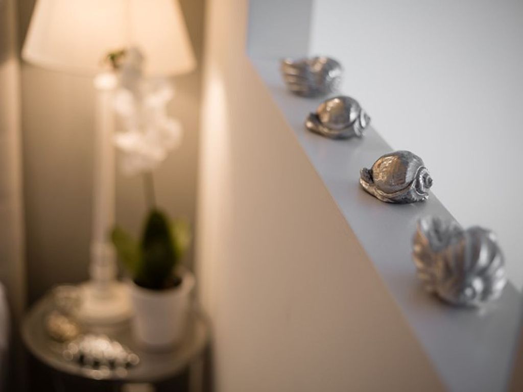 A room with a lamp, a potted plant, and decorative shells on a table.