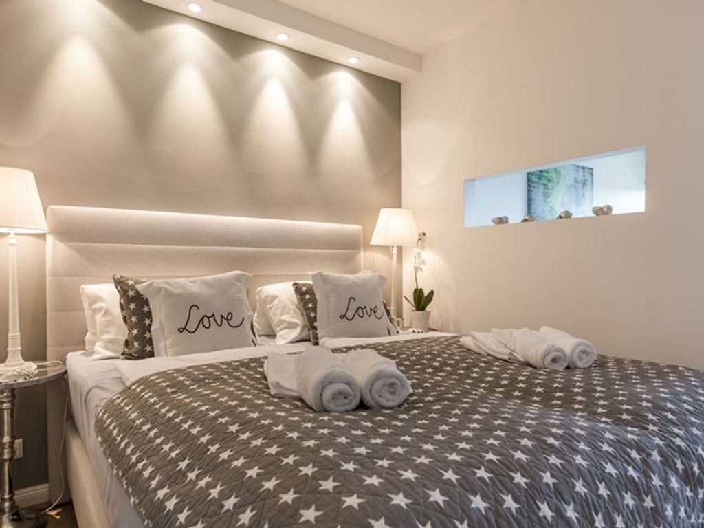 A neatly made bed with star-patterned bedding and pillows with the word "Love" on them.