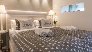 A neatly made bed with star-patterned bedding and pillows with the word "Love" on them. - New Port II - Newport on the beach with south-facing balcony and dune view (Sylt)