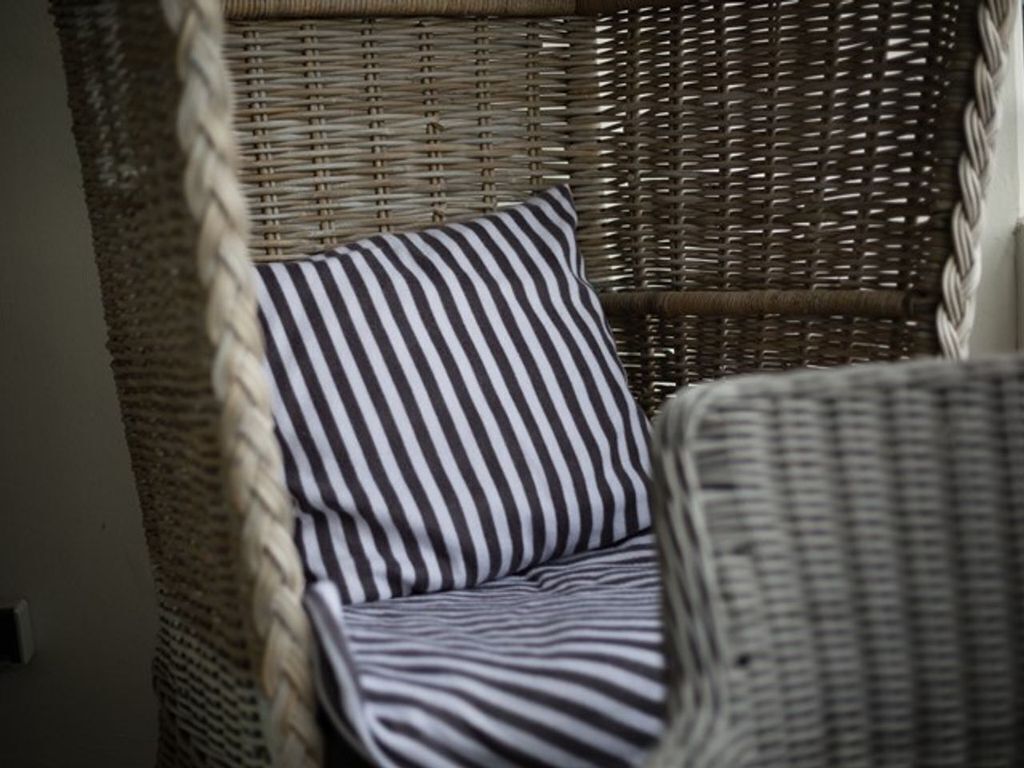 Una silla de mimbre con un cojín a rayas.