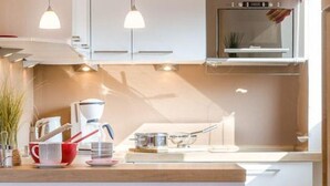 A modern kitchen with white cabinets, a wooden countertop, and a built-in oven. - Nordstern - 1-room apartment with balcony and beach chair in the immediate vicinity (Sylt)
