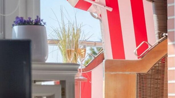 A room with a striped awning, a potted plant, and a wicker chair. - Nordstern - 1-room apartment with balcony and beach chair in the immediate vicinity (Sylt)
