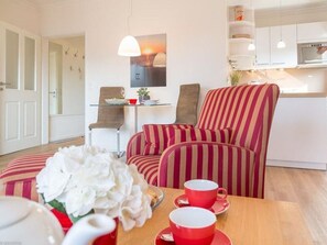 Un salon chaleureux avec un canapé à rayures, une petite table avec des tasses rouges et un tableau accroché au-dessus du canapé.
