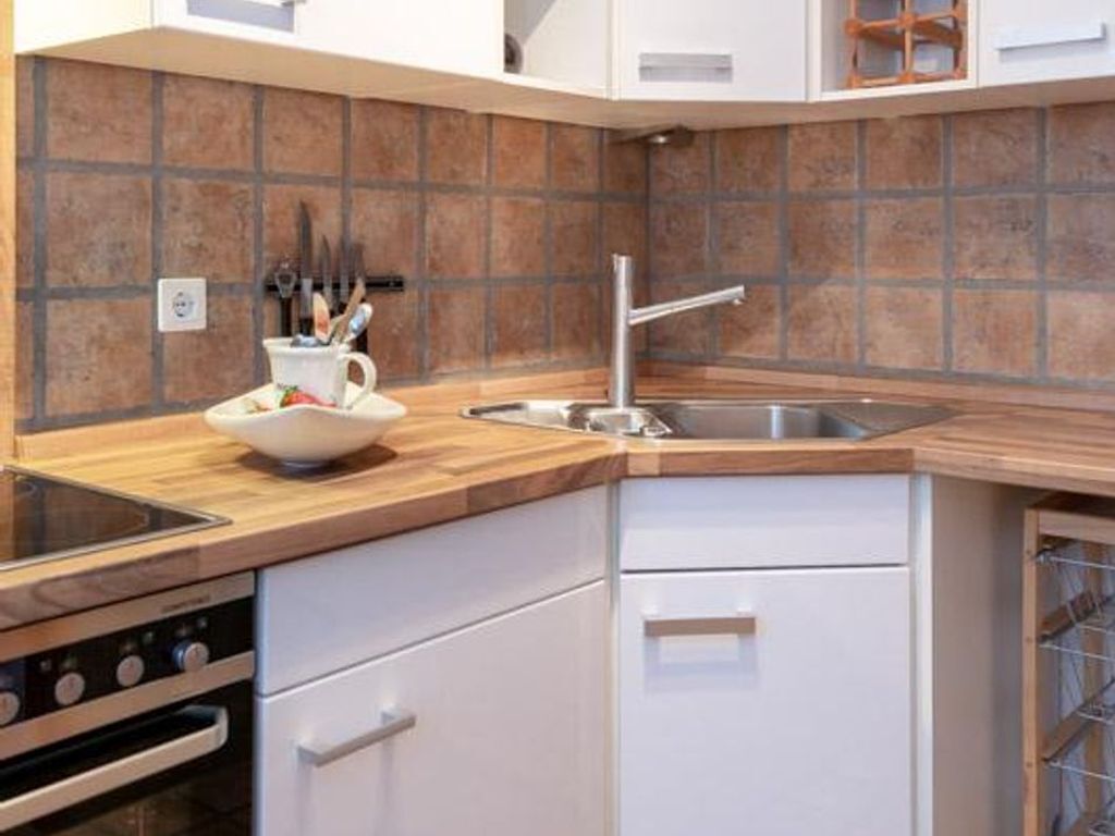 A kitchen with a wooden countertop, a sink, and a stove.