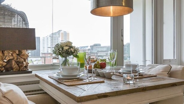 A dining table set with plates, glasses, and a vase of flowers.