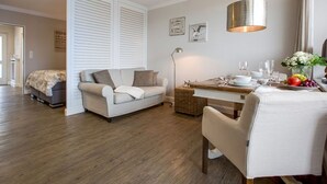 A modern living room with a sofa, a dining table, and a lamp.
