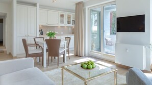 A modern living room with a glass coffee table, white sofas, and a dining area with wicker chairs. - Viktoria Residence, App. 10 - Top city location: Very comfortable, bright 2 (Sylt)