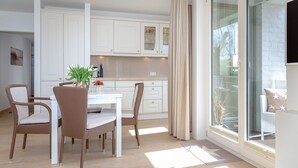 A modern kitchen with white cabinets, a dining table with four chairs, and a large sliding glass door to a balcony. - Viktoria Residence, App. 10 - Top city location: Very comfortable, bright 2 (Sylt)