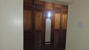 Ein Holzschrank mit Spiegel, Lichtschalter und Fliesenboden.