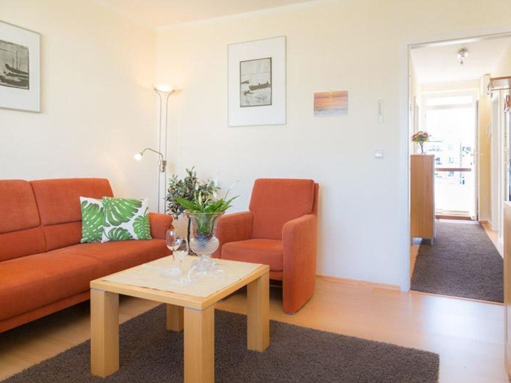 Una sala de estar con sofá, sillón, mesa de centro y una planta.