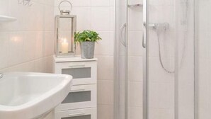 Ein Badezimmer mit Waschbecken, Spiegel, Pflanze und Dusche.