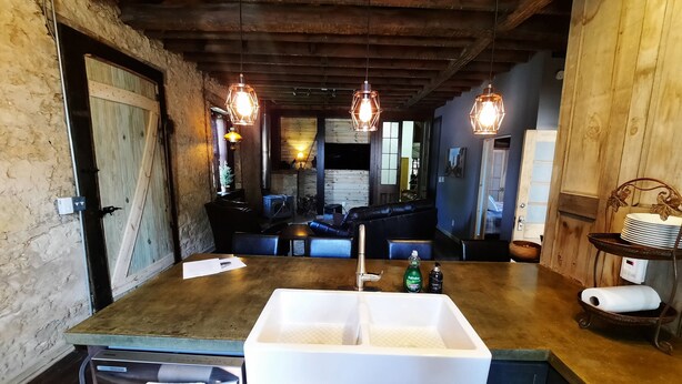A rustic kitchen with a large island, wooden ceiling, and pendant lighting. - Primitive yet classy apartment in rural Iowa near small town shopping and hiking (Colesburg)