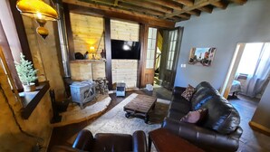 A cozy living room with a fireplace, leather sofa, and a television. - Primitive yet classy apartment in rural Iowa near small town shopping and hiking (Colesburg)