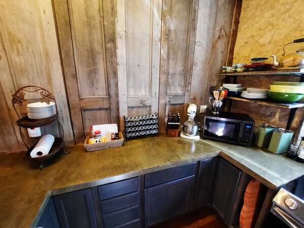 A kitchen with wooden cabinets, a microwave, a coffee maker, and various kitchen utensils. - Primitive yet classy apartment in rural Iowa near small town shopping and hiking (Colesburg)