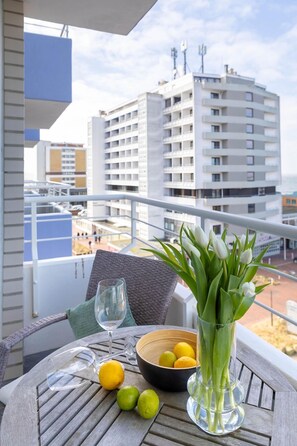 A balcony with a table, a vase with flowers, a glass, and a bowl of lemons. - Dwarslöper 2 - 2 room apartment on the beach - Outstanding sea view from the 5th floor (Sylt)