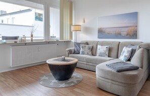 Een woonkamer met een ronde salontafel, een bank, een lamp en een schilderij aan de muur.