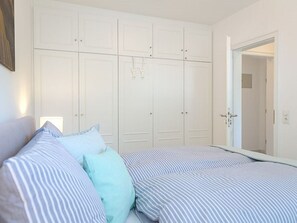 Un dormitorio con cama, armario y espejo.