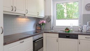 Et moderne køkken med hvide skabe, ovn i rustfrit stål og opvaskemaskine.